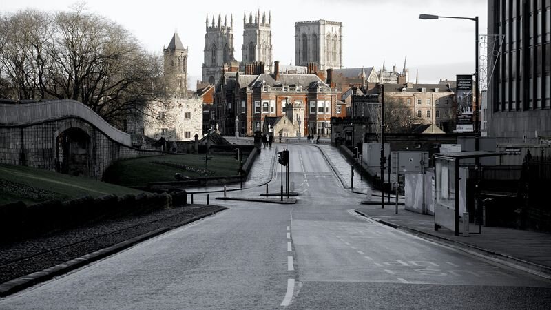A Gothic cathedral with twin towers rising above rooftops at the end of an empty city street